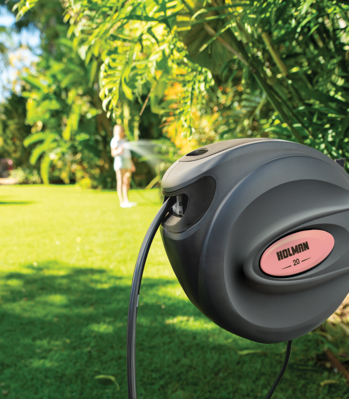Charcoal 20m Retractable Hose Reel installed in garden with papaya coloured side insert