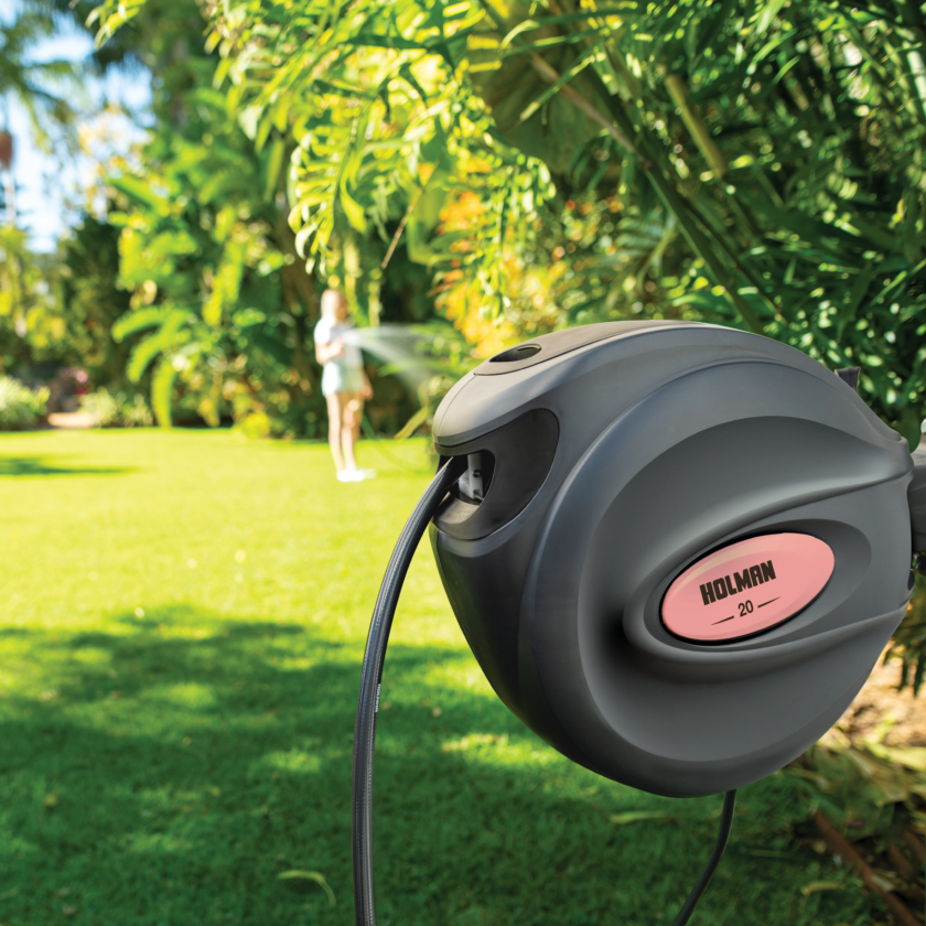 Charcoal 20m Retractable Hose Reel installed in garden with papaya coloured side insert