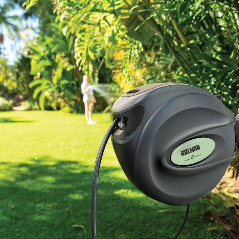 Charcoal 20m Retractable Hose Reel installed in garden with sage coloured side insert