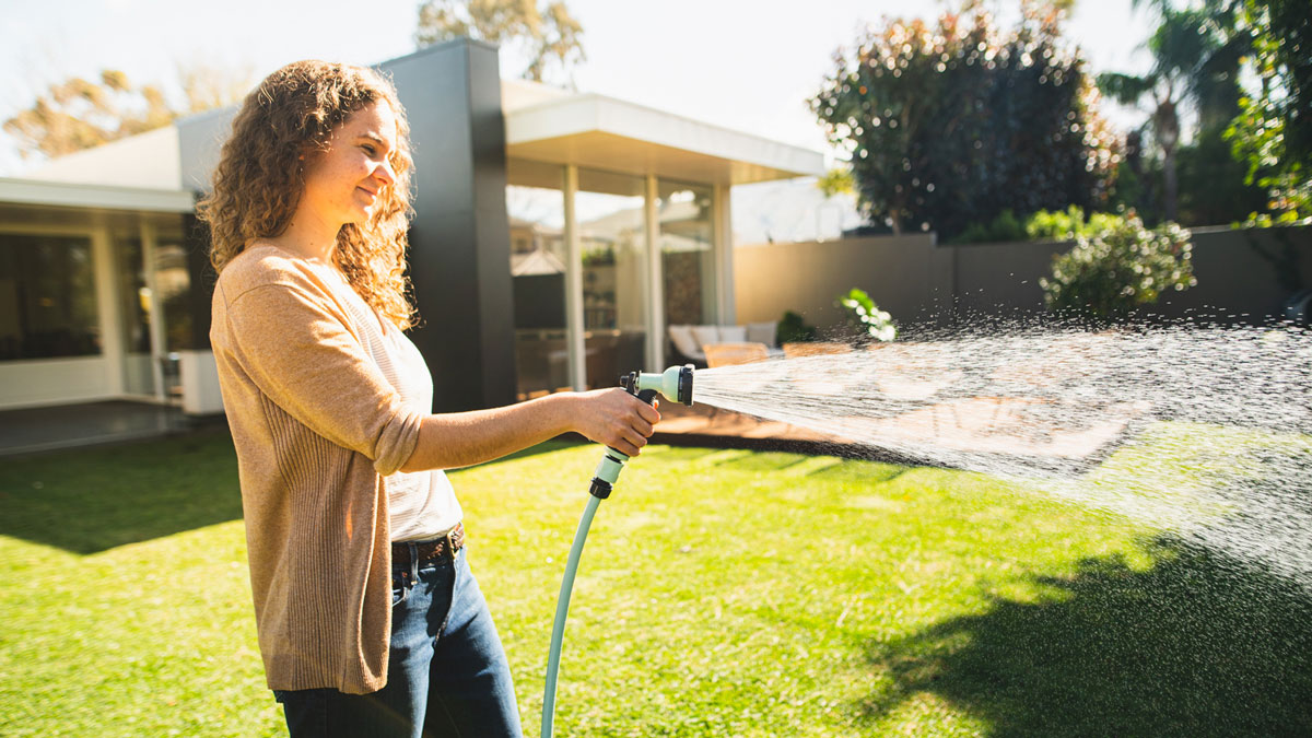 watering lawn with sage green hose and matching spray gun